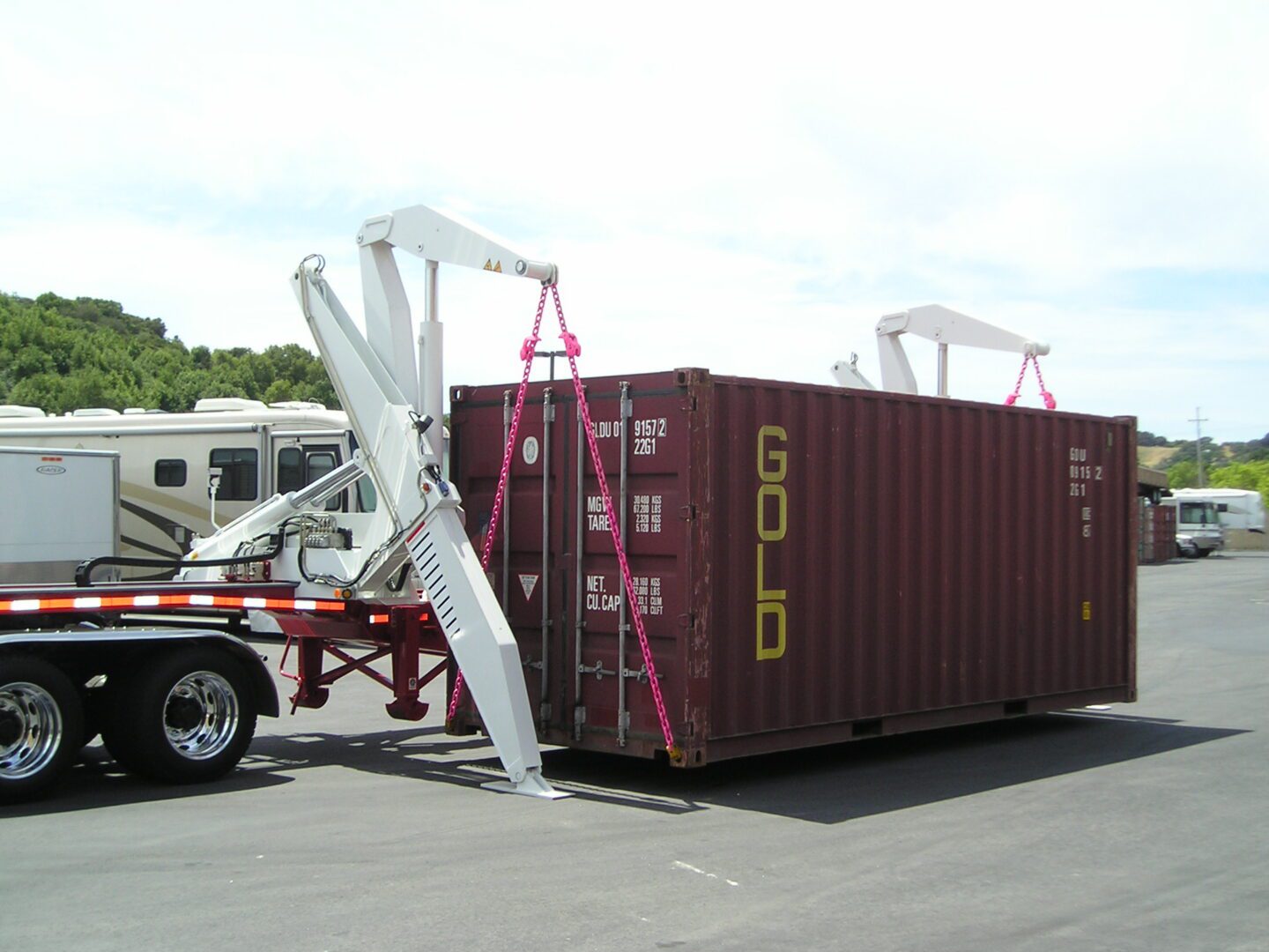Truck with a crane on the back of it, lifting a container onto the road