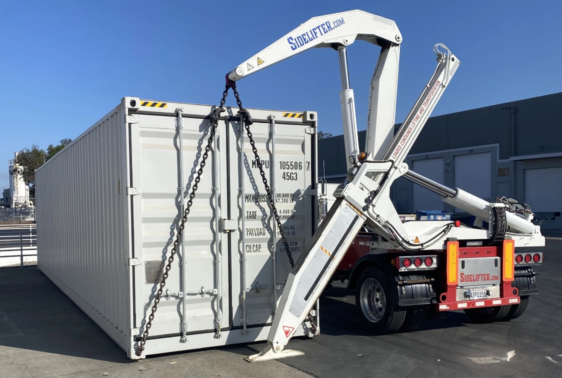 White truck parked in front of a building with a crane on the back of it
